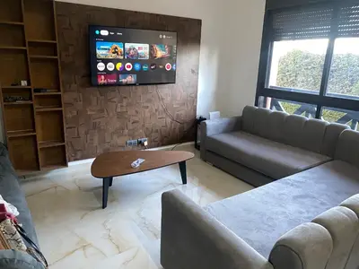 a living room with a couch and a tv at Cosy appartement avec piscine in Marrakech