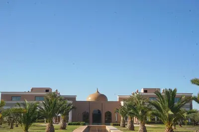 a building with palm trees in front of it at Palais Les Orchidées - Villa de Luxe à 15 minutes du Centre in Marrakech
