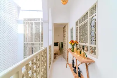 a hallway with a staircase with a table and flowers at Riad Grenade Exclusif Front Bahia in Marrakech