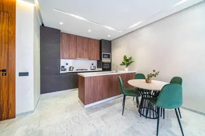 a kitchen with a table and some green chairs at Cute and Modern in Heart of Downtown in Marrakech
