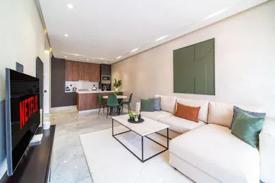 a living room with a white couch and a tv at Cute and Modern in Heart of Downtown in Marrakech