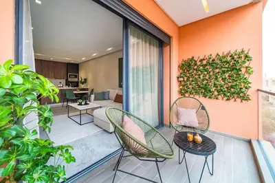 an apartment balcony with chairs and a living room at Cute and Modern in Heart of Downtown in Marrakech
