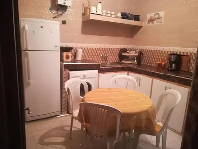 a kitchen with a table and chairs and a white refrigerator at Spacious Apt - Near Airport - Perfect for Groops! in Marrakech