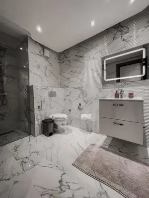 a bathroom with marble walls and a sink and a toilet at Luxury Appartement in Marrakech
