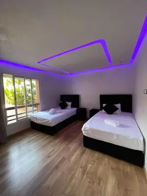 two beds in a room with purple lights at Luxury Appartement in Marrakech