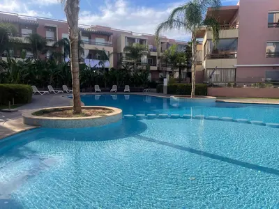 a large swimming pool with a palm tree in front of a building at Luxury Appartement in Marrakech