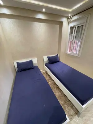 two beds in a room with blue sheets and a window at Appartement Zen in Marrakech