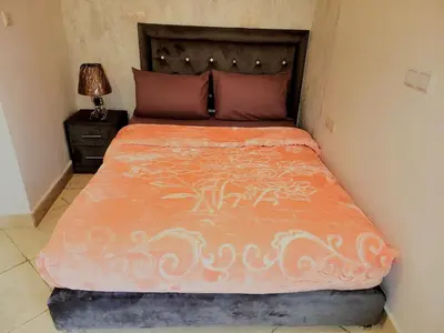 a bed with an orange comforter in a bedroom at Authentic stay 2 in Marrakech Comfort & Charm in Marrakech