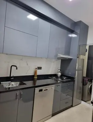 a kitchen with white cabinets and a sink and a refrigerator at Appartement a les portes de gueliz in Marrakech
