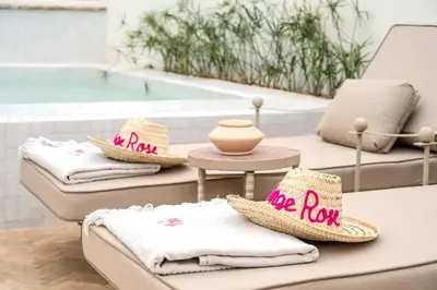 a group of towels and hats on a table next to a swimming pool at Le Singe Rose & SPA in Marrakech