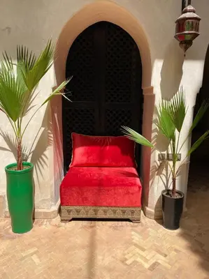a red couch sitting in a room with two plants at Riad Palais Bahia - Entire House - 5 Bedrooms in Marrakech