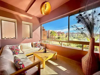 a living room with a couch and a large window at Exceptional Golf View Apartment, Prestigia in Marrakech