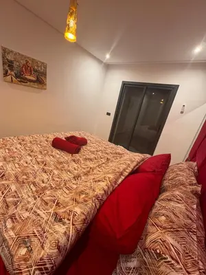 a bedroom with a bed with red pillows on it at Appartement Naïel Palmeraie avec piscine in Marrakech