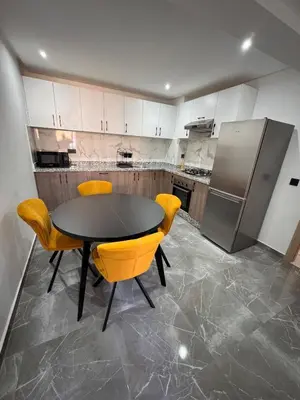 a kitchen with a table and chairs and a refrigerator at Appartement Naïel Palmeraie avec piscine in Marrakech