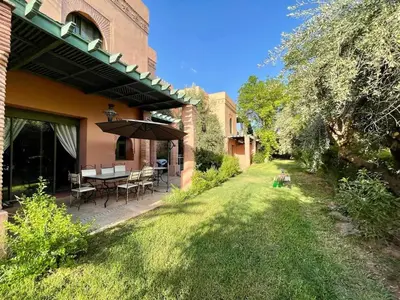 a patio with a table and an umbrella in a yard at Appartement à Marrakech in Marrakech