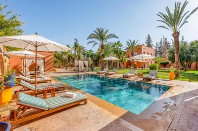 a swimming pool with lounge chairs and umbrellas at Villa Simari Palmeraie Marrakech NOUVEAU! Petit déjeuner compris-Entièrement rénovée-Superbe piscine privée chauffée-Personnel de maison inclus-Grand jardin de 2000m2-Terrain de pétanque-Ambiance typique berbère-Havre de paix in Marrakech