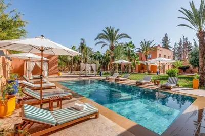 a swimming pool with lounge chairs and umbrellas at Villa Simari Palmeraie Marrakech NOUVEAU! Petit déjeuner compris-Entièrement rénovée-Superbe piscine privée chauffée-Personnel de maison inclus-Grand jardin de 2000m2-Terrain de pétanque-Ambiance typique berbère-Havre de paix in Marrakech