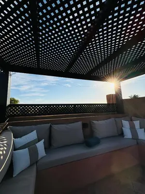 a couch sitting under a pergola on a balcony at Dar Sawan - Beautiful 2rooms & terrace at Atlas golf Palmeraie in Marrakech