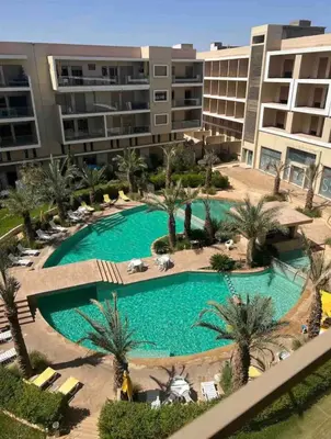 an overhead view of a pool with palm trees and buildings at Perl garden in Marrakech