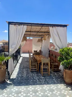 a patio with a table and chairs under a canopy at Riad dar lakbira in Marrakech