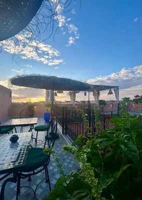 a patio with tables and chairs and an umbrella at Riad dar lakbira in Marrakech