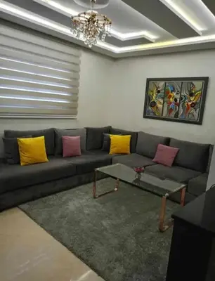 a living room with a gray couch with yellow and pink pillows at appartement meuble in Marrakech