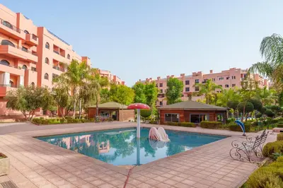a swimming pool with an umbrella and some buildings at Luxury Residence with 2 Terraces Pool and Garden View Security and Self Check-in in Marrakech