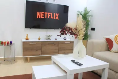 a living room with a tv and a vase of flowers on a table at Modern central apartment 2 bedrooms in Marrakech