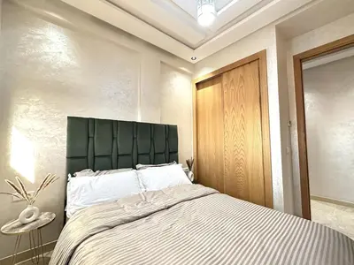 a bedroom with a large bed with a green headboard at New and modern apartment in Marrakech