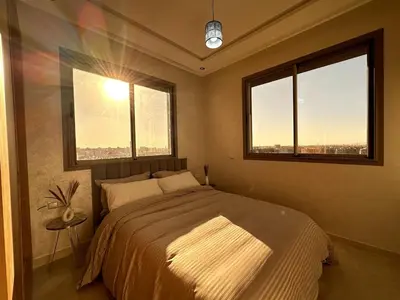 a bedroom with a large bed and two windows at New and modern apartment in Marrakech
