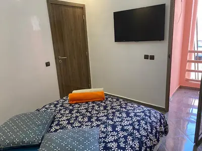 a bedroom with a bed with an orange pillow and a flat screen tv at Location appartement a Marrakech aboib gulez in Marrakech