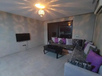 a living room with a couch and a tv at Appartement calme, proche de toutes commodités in Marrakech