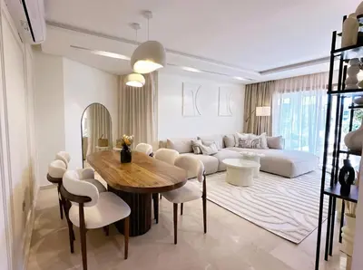 a living room with a couch and a table and chairs at Prestigia Saphir Luxury 3 Bedrooms, Pool & Golf View, near Airport in Marrakech