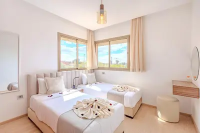 two beds in a white room with windows at Appât hôtel in Marrakech