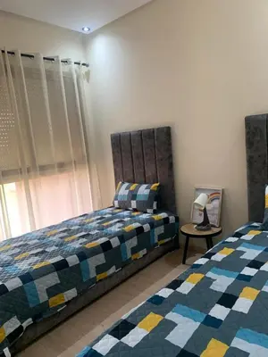 a bedroom with two beds and a table with a lamp at prestigia agate apt haut standing meublé in Marrakech