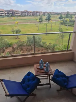 a balcony with two chairs and a table and a view of a field at prestigia agate apt haut standing meublé in Marrakech