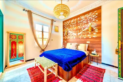 a bedroom with a blue bed and a chandelier at Palais Rhize targa in Marrakech