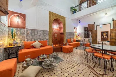 a lobby with orange furniture and a table and chairs at Riad Khadoj-Marrakech-Traditional in Marrakech
