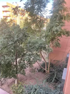 a view of a garden with trees and a building at Furnished apartment close to the city center in Marrakech