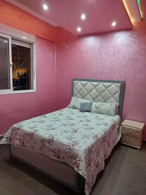a bedroom with a bed with a pink wall at Furnished apartment close to the city center in Marrakech