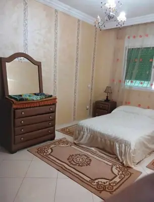 a bedroom with a bed and a dresser and a mirror at appartement meuble in Marrakech