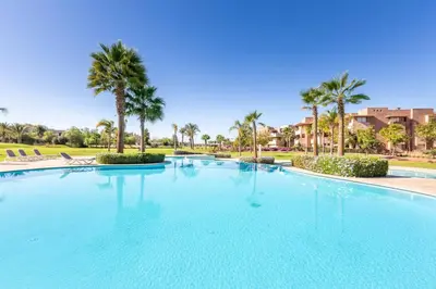 a large swimming pool with palm trees in a resort at Waterfront - Garden Level - Prestigia in Marrakech