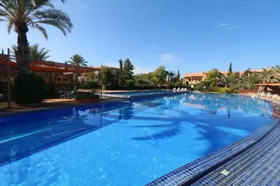 a large swimming pool with blue water and palm trees at Luxe et Detente Haut standing Piscine in Marrakech