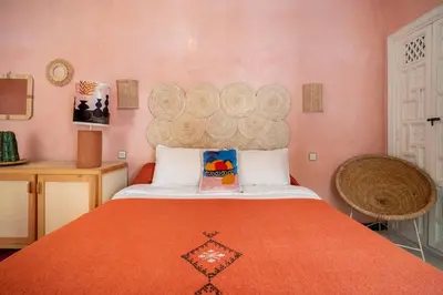a bedroom with a large bed with an orange blanket at Riad Dar Chalyia, private, 6 people, pool in Marrakech