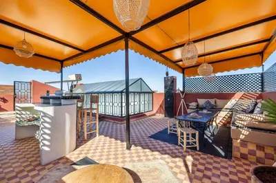 an outdoor patio with a roof with a table and chairs at Riad el hana en centre ville rooftop et bassin in Marrakech
