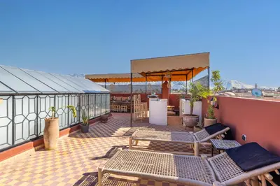 a patio with chairs and tables on a roof at Riad el hana en centre ville rooftop et bassin in Marrakech
