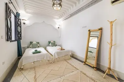 a bedroom with two beds and a mirror at Riad el hana en centre ville rooftop et bassin in Marrakech