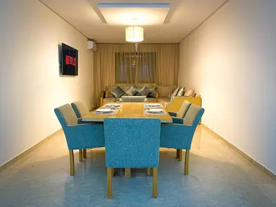 a dining room table with blue chairs and a couch at Luxury Aprt 2 bedrooms Pool Hivernage City Centre in Marrakech