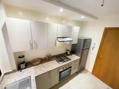 a small kitchen with white cabinets and a refrigerator at Luxury Aprt 2 bedrooms Pool Hivernage City Centre in Marrakech