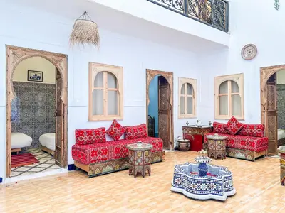 a living room with red couches and a table at Riad Sifaw & Spa Marrakech in Marrakech